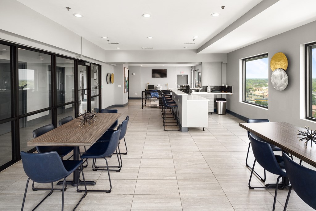 a communal area with tables and chairs and a kitchen in the background at Elevate 758, Mobile, 36602