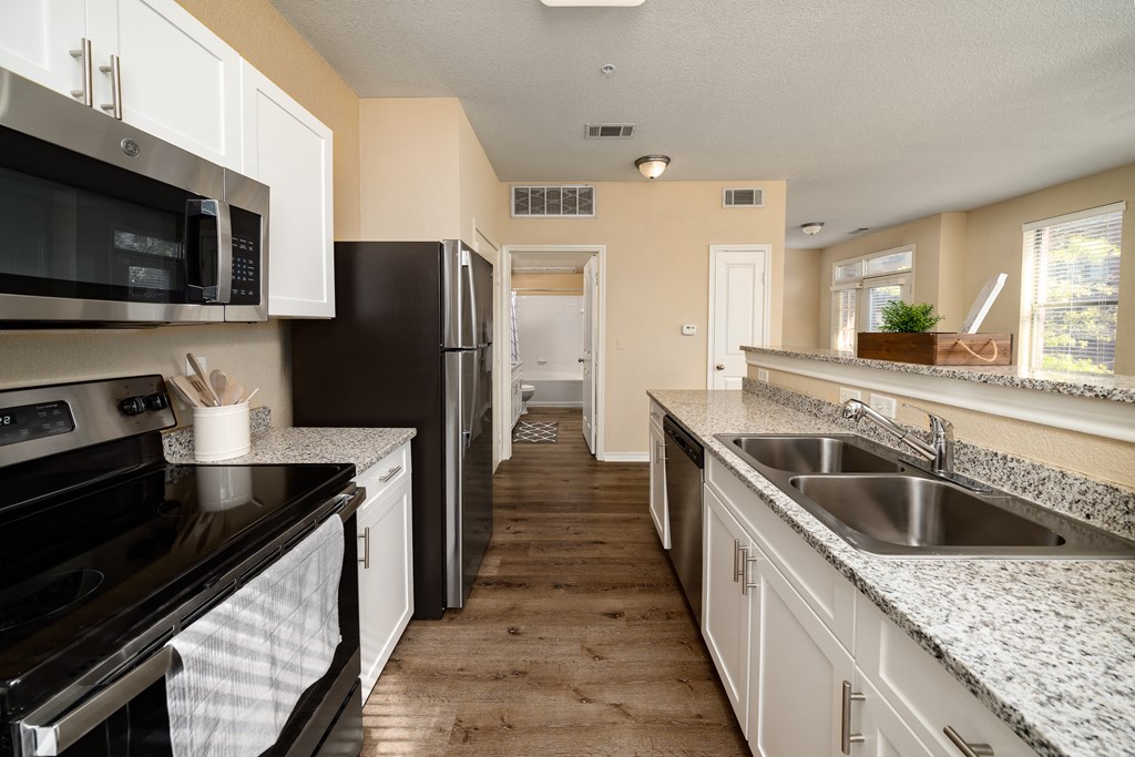 full kitchen with granite counter tops and stainless steel appliances and white cabinets