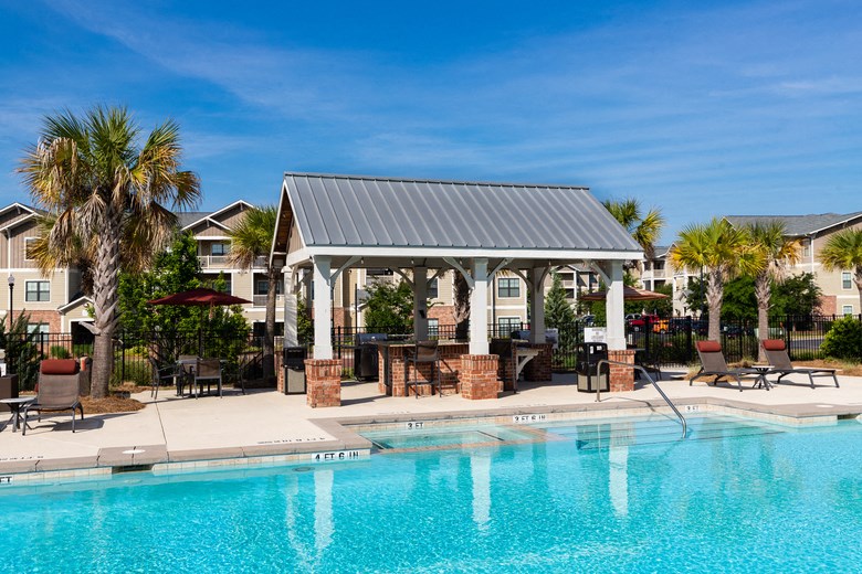 a swimming pool with a gazebo and chairs near a resort style pool