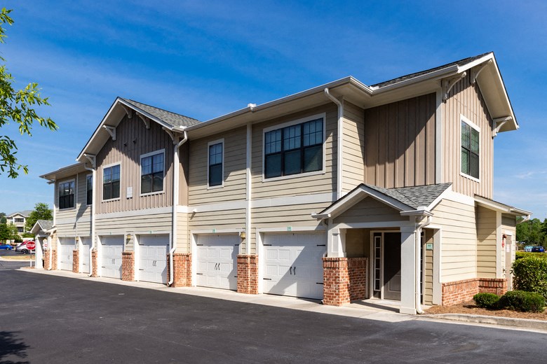 the exterior of a building with white doors and tan siding