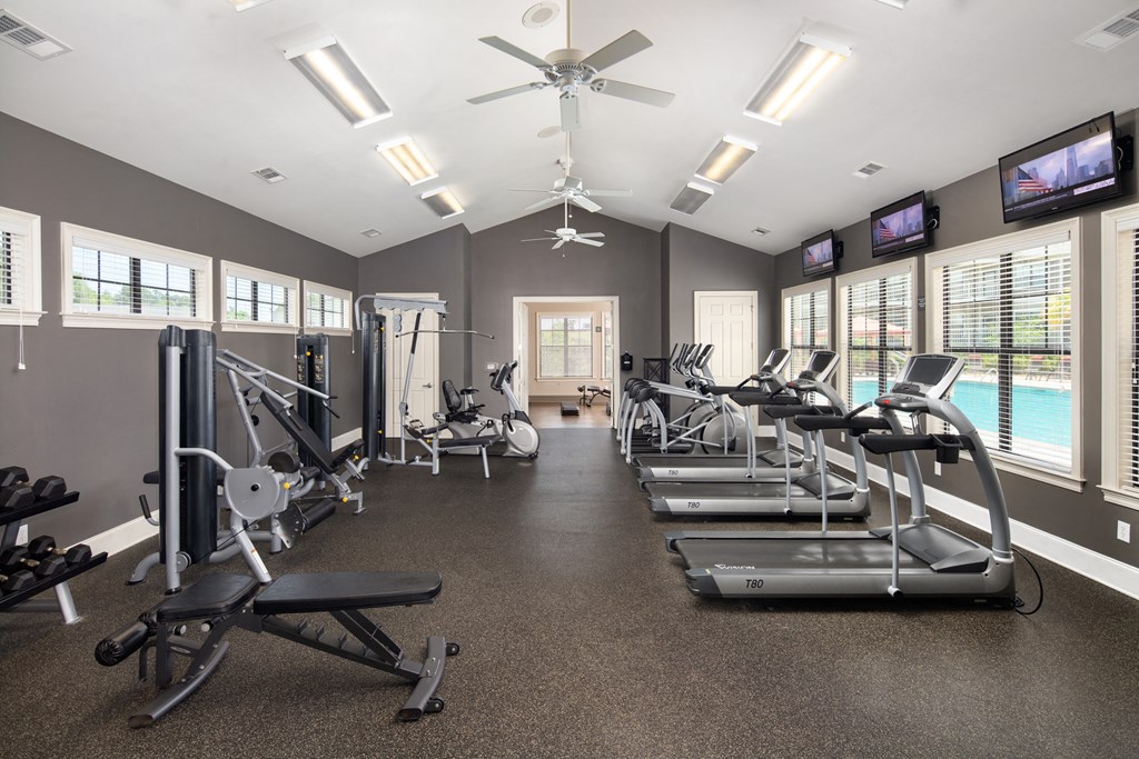 a gym with cardio equipment and windows and a pool