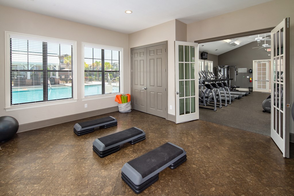 a workout room with weights and a pool in the background