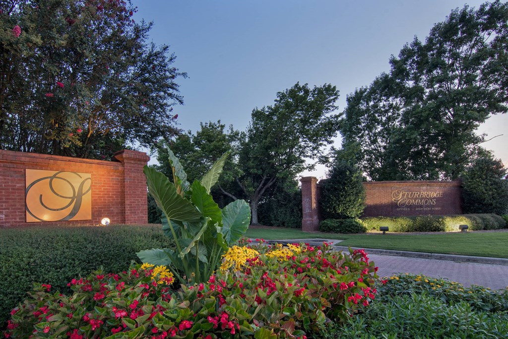 a building with a sign and flowers in front of it