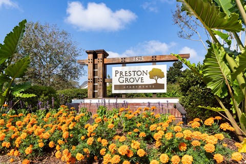 a sign in front of a garden of flowers