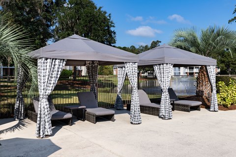 two gazebos with chairs and curtains on a patio