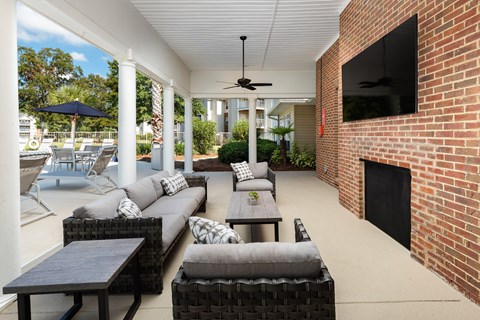 a patio with couches and tables and a brick fireplace