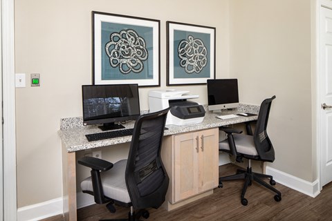 a desk with two computers and a printer on it in a room