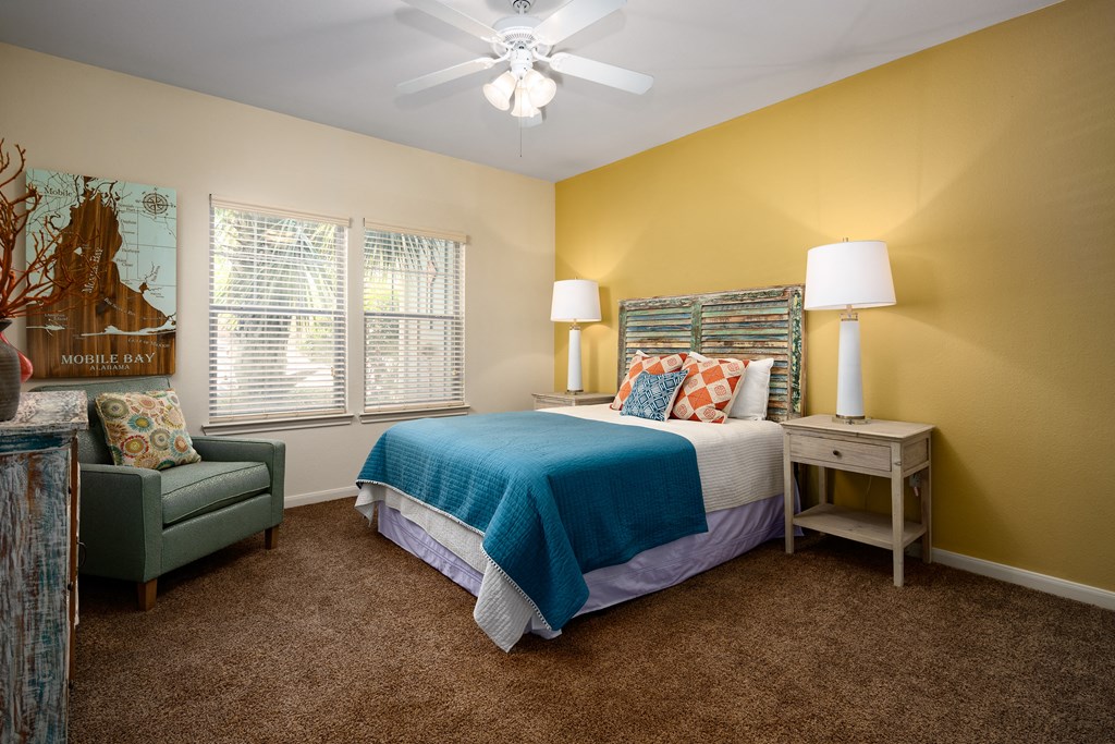a bedroom with a bed and a chair and a ceiling fan