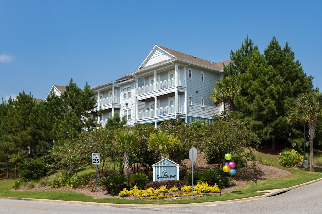 a large blue house on a hill with flowers and trees