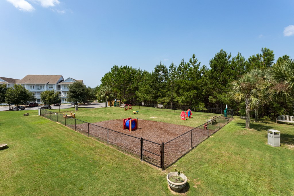 a fenced in park with playground equipment and kids in it