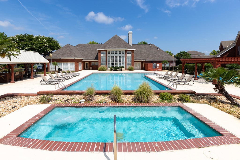 a swimming pool with chairs around it in front of a house