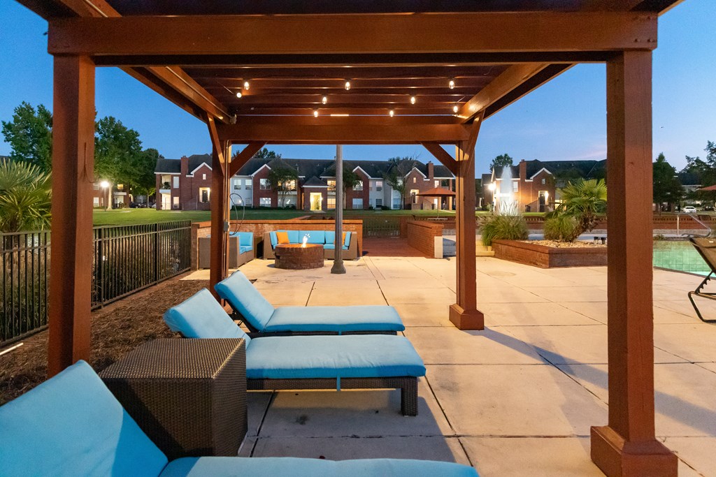 a covered patio with couches and a pool at night