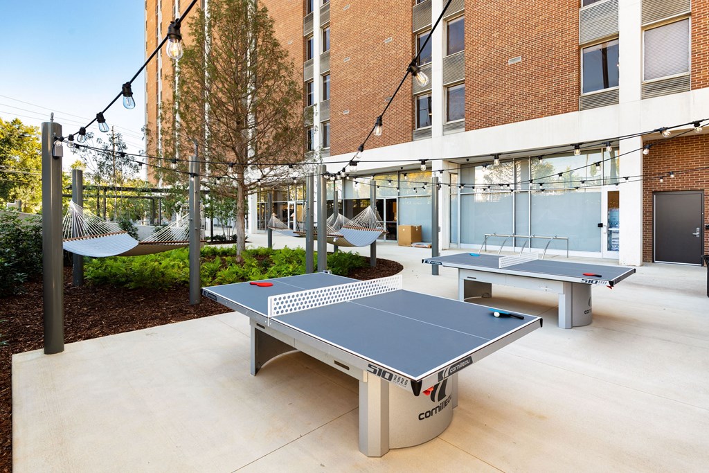 two ping pong tables in the courtyard of an office building with other amenities