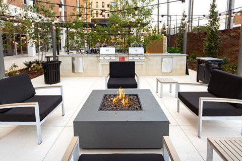 A modern outdoor seating area with a fire pit in the center at Tower on Tenth Apartments, Alabama