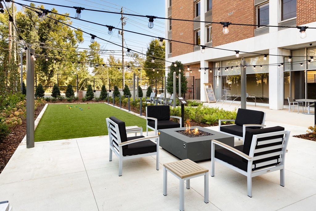 a patio with chairs and a fire pit in front of a building