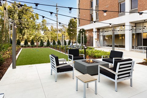 a patio with chairs and a fire pit in front of a building at Tower on Tenth Apartments, Birmingham 35205