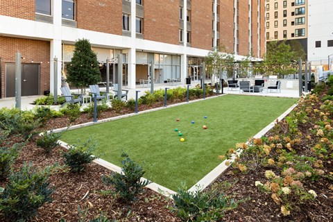 A green lawn with a white fence and a building in the background at Tower on Tenth Apartments, Birmingham
