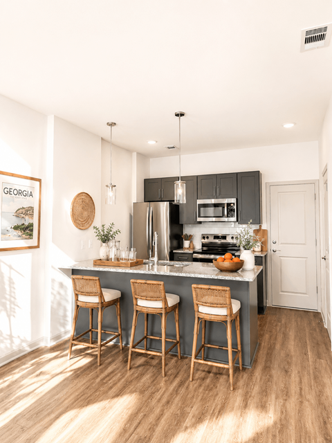 A kitchen with a grey island and wooden chairs.