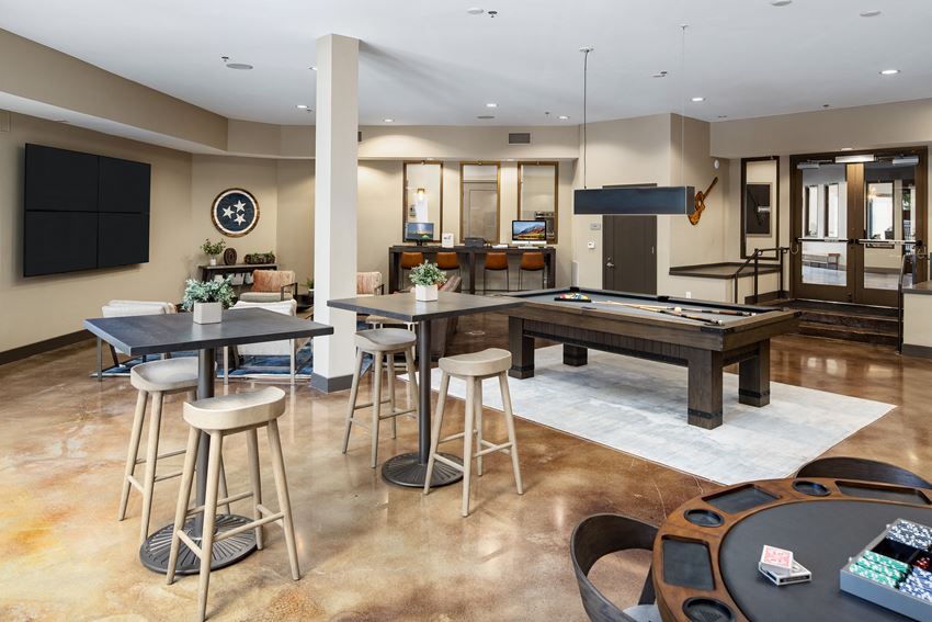a clubhouse with a pool table and a bar with bar stools