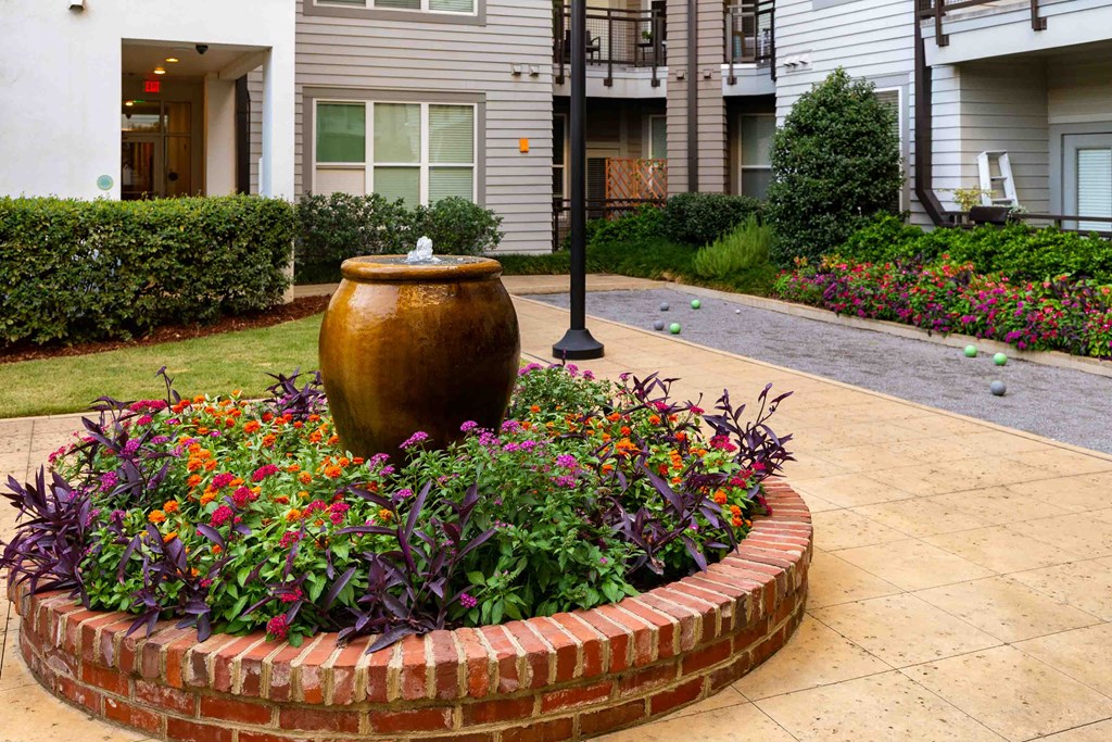 a garden with a vase and flowers in front of a house