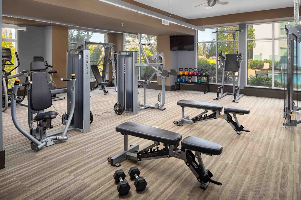 a gym with weights and other exercise equipment in a large room with windows