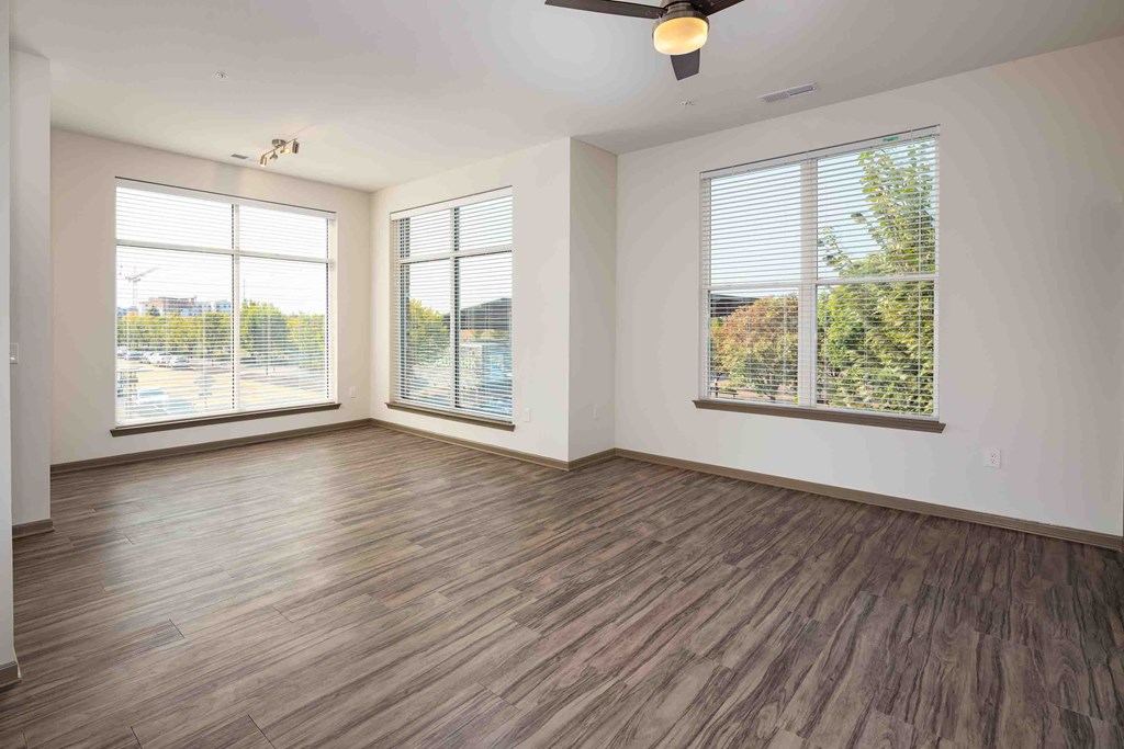 an empty living room with wood floors and windows