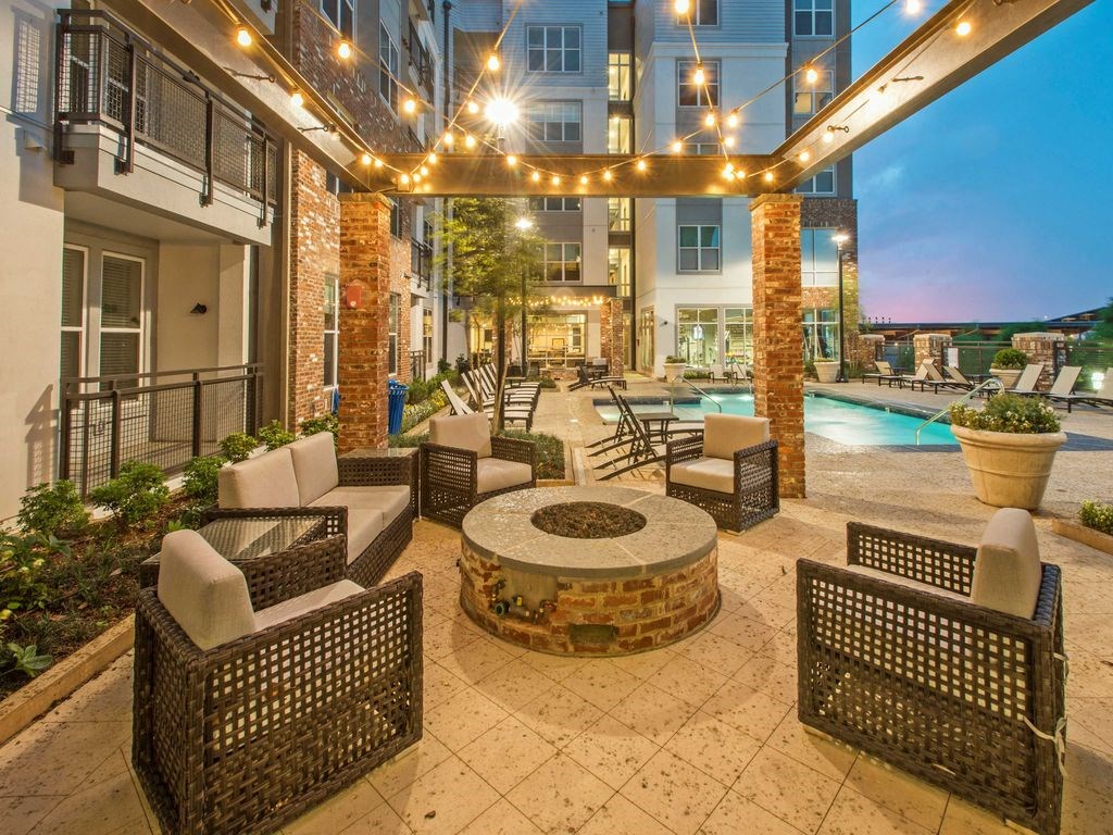 a patio with chairs and a fire pit at night