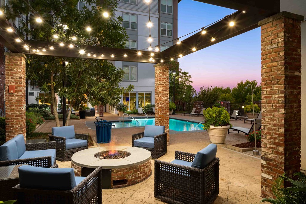 an outdoor patio with chairs and a fire pit at night