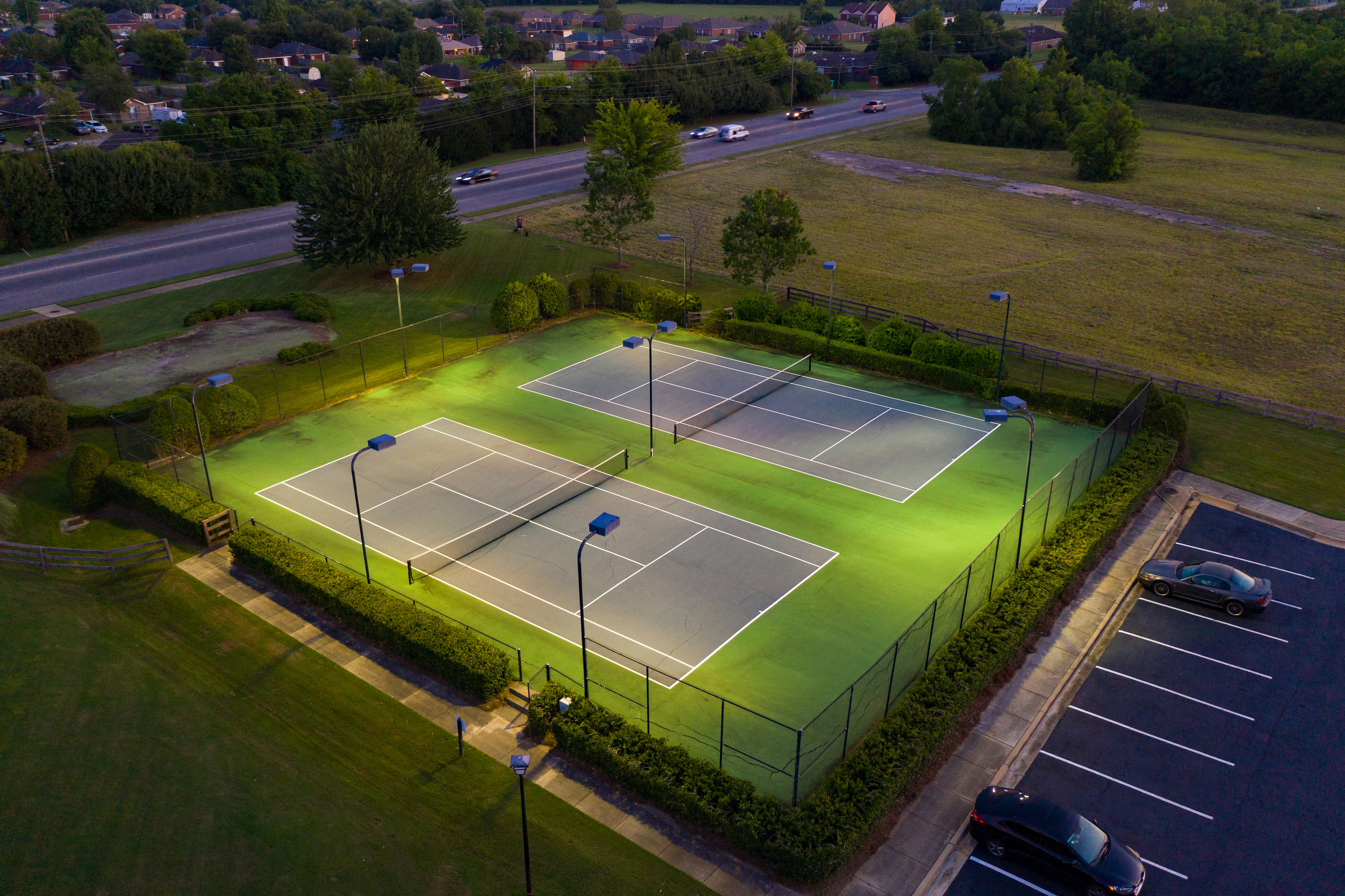 an aerial view of a tennis court on a green field