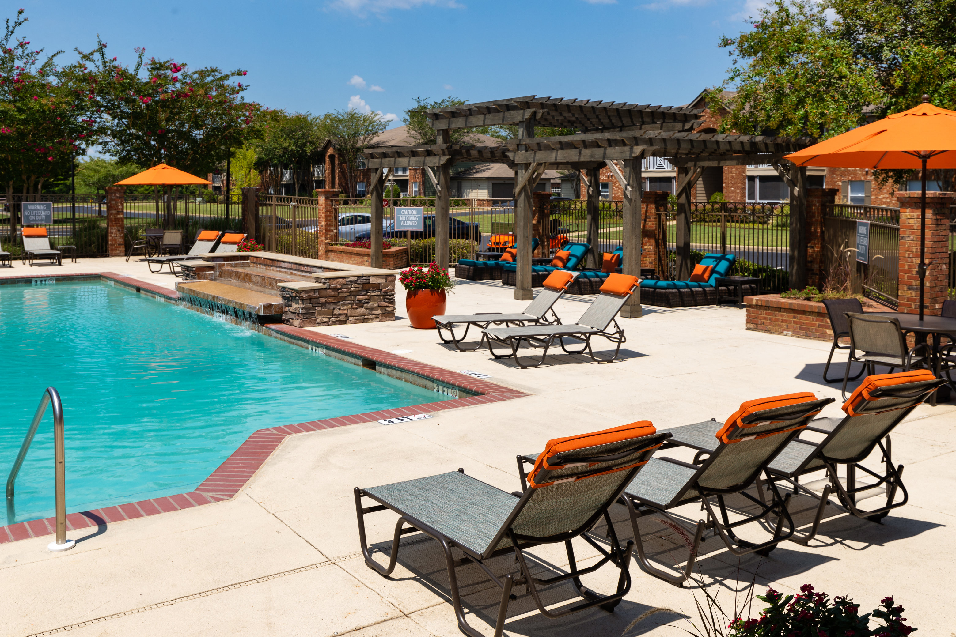 a swimming pool with chairs and umbrellas near a resort style pool
