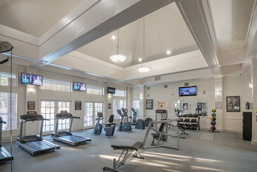 a gym with treadmills and other exercise equipment and televisions