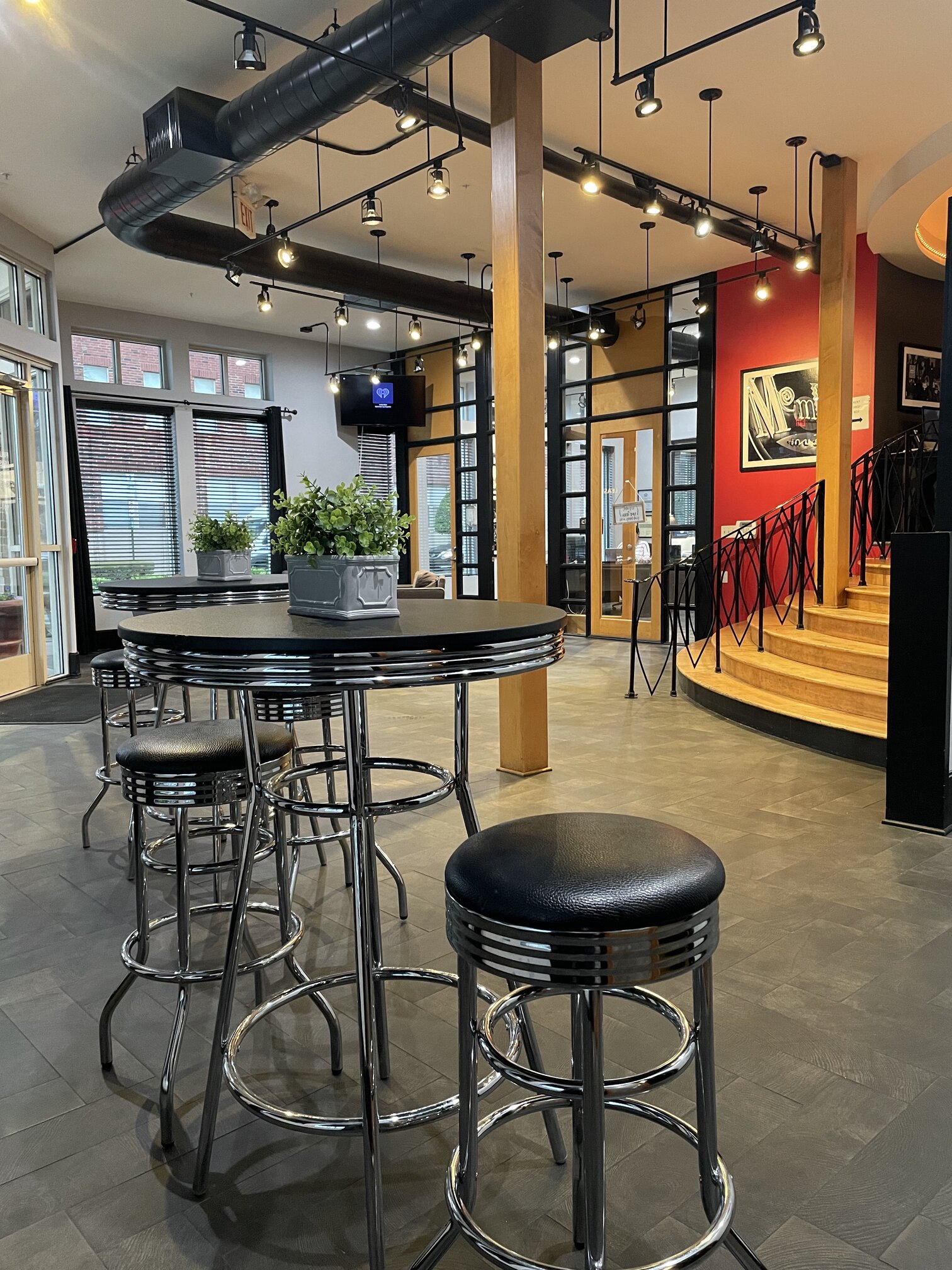 a bar with stools in the lobby of a building with a staircase