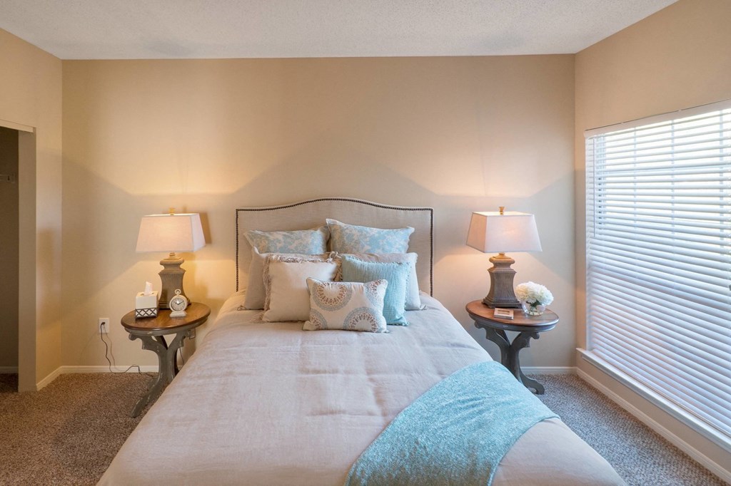 a bedroom with a bed and two lamps and a window