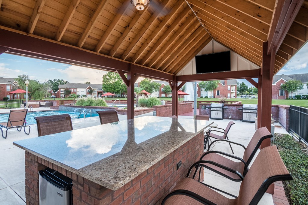 a patio with a bar and a pool with chairs