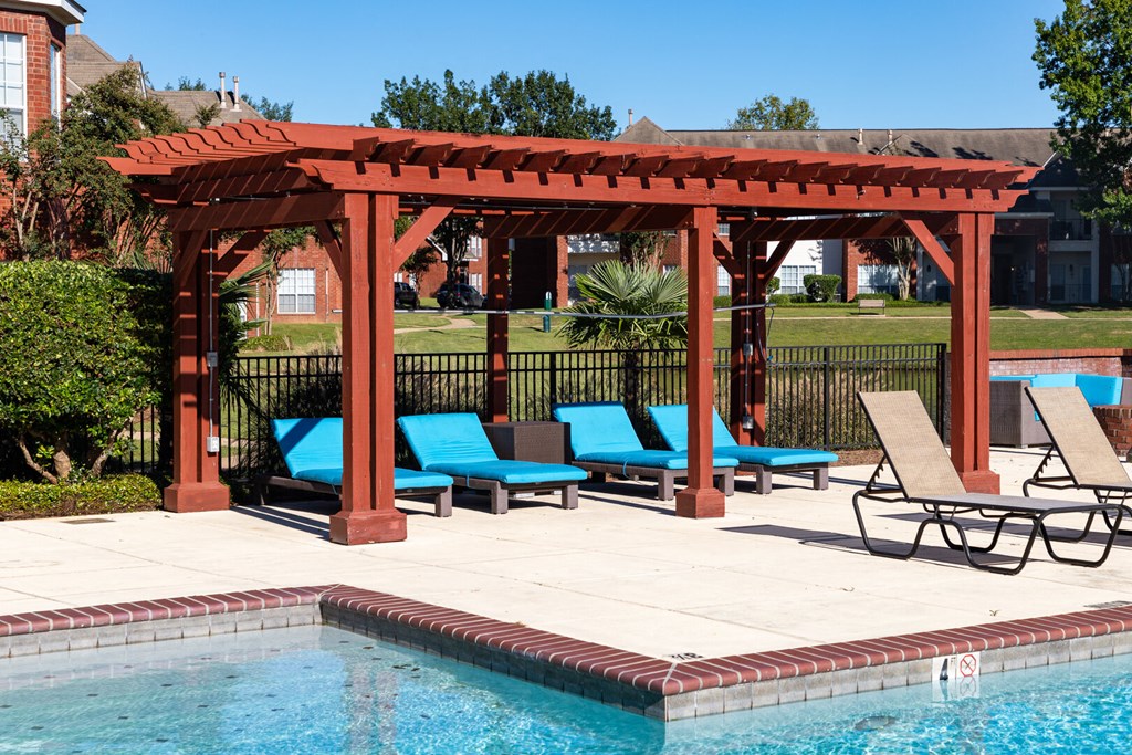 a wooden pergola with lounge chairs next to a swimming pool
