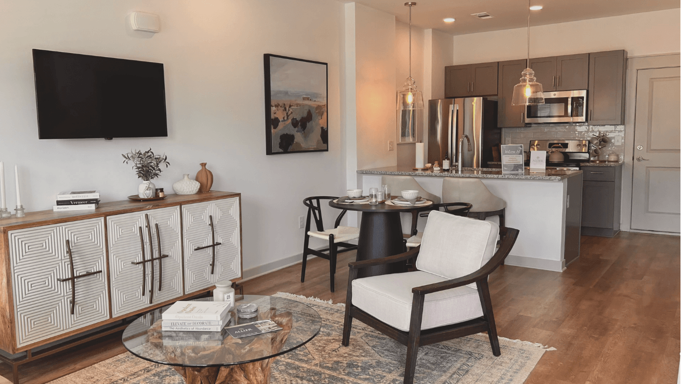 A modern living room with a glass coffee table and a TV mounted on the wall.