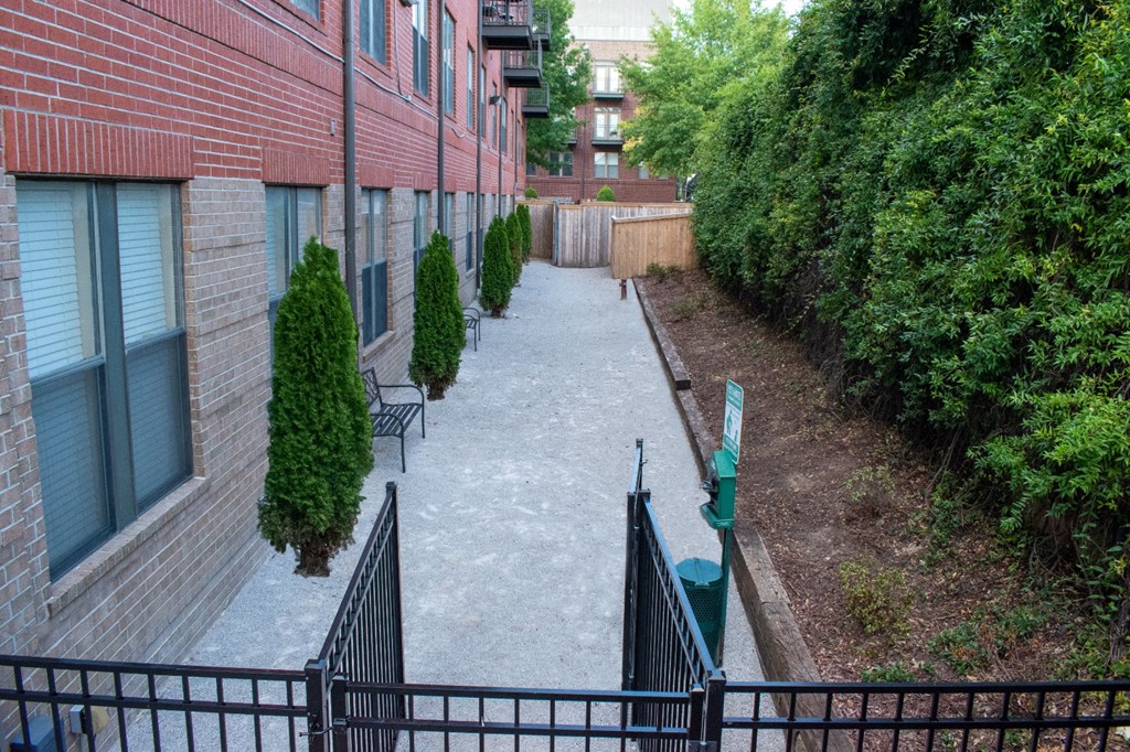 a walkway between two buildings with a bench and trees