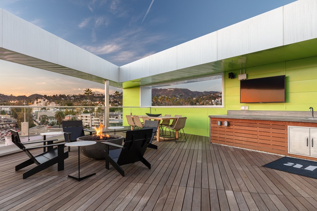 a rooftop deck with tables and chairs and a fire pit