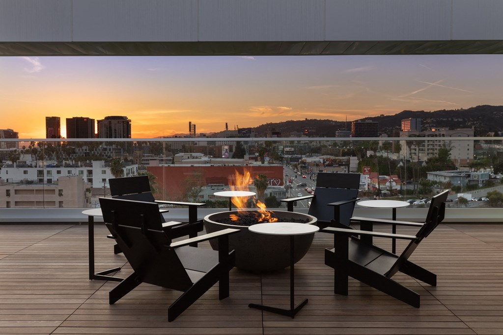 a terrace with a fire pit and a view of the city at sunset