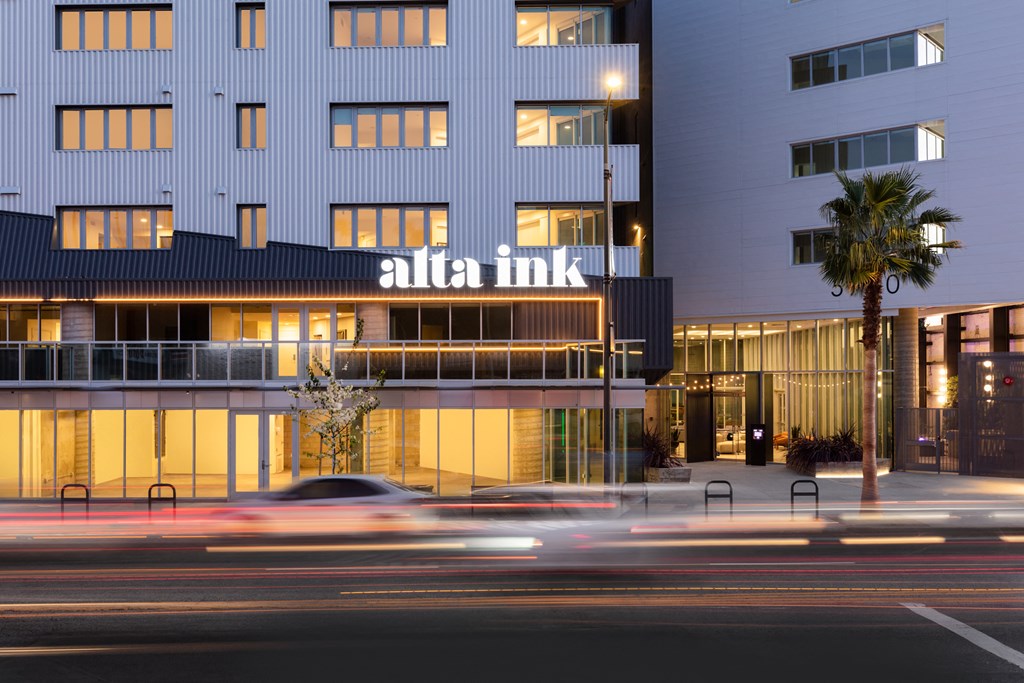 the facade of a hotel at night with a car driving past