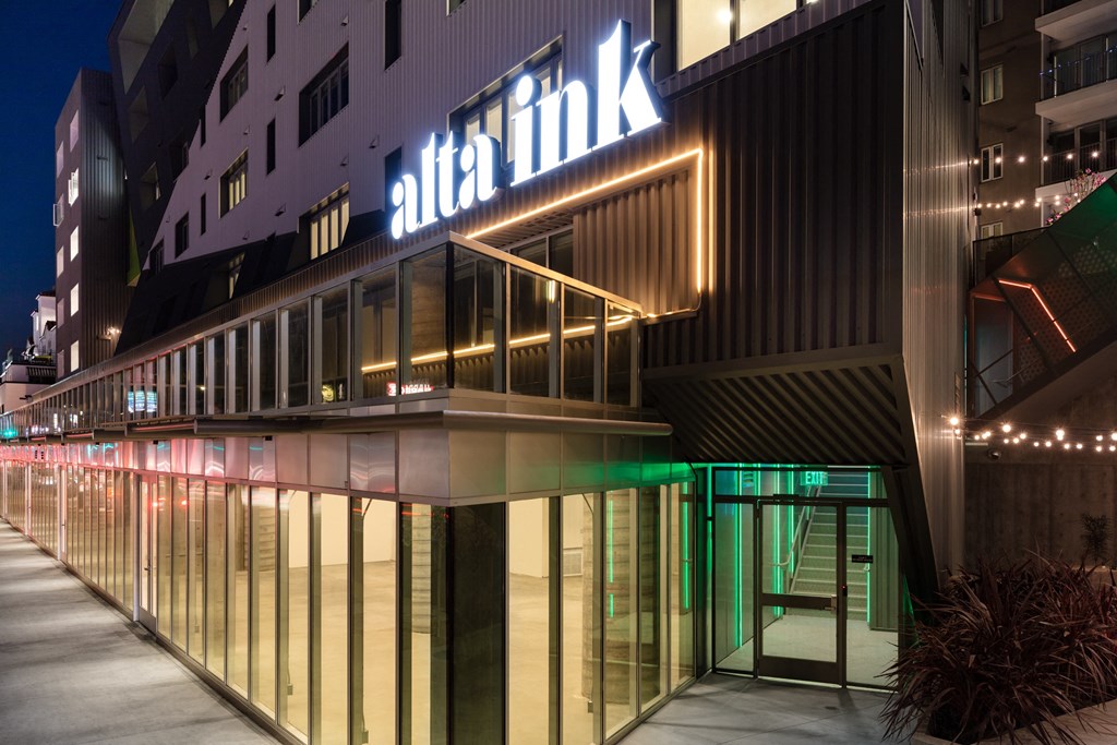 the facade of a hotel at night with a lit up sign on the side of