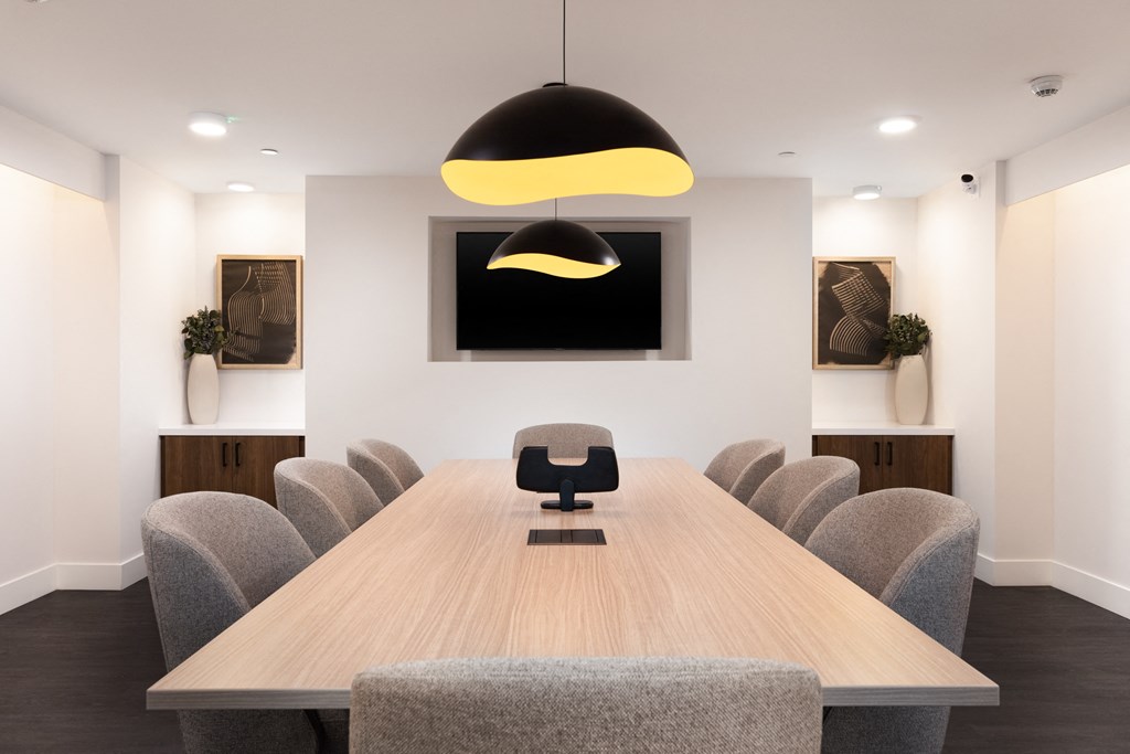 a conference room with a wooden table and chairs and a tv on the wall