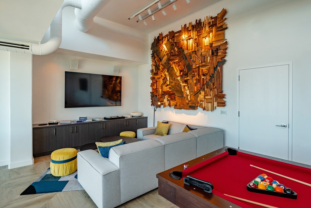 a living room with a pool table and a large artwork on the wall