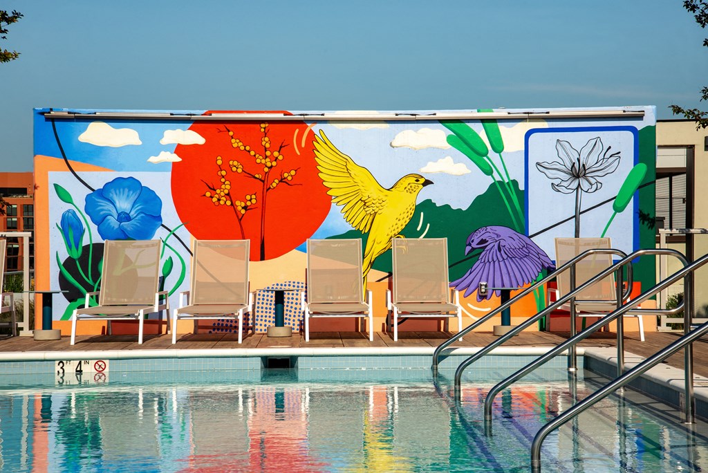 a colorful mural on the side of a building next to a pool