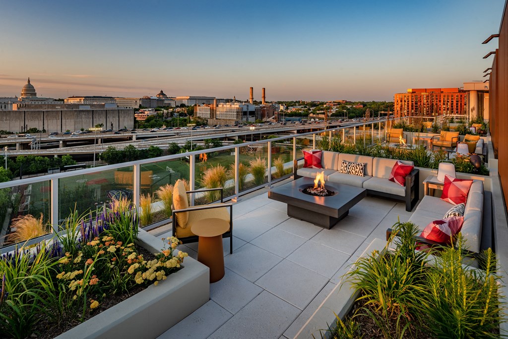 a roof deck with couches and a fire pit overlooking the city