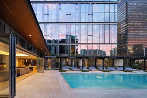 A modern building with a pool and lounge chairs.