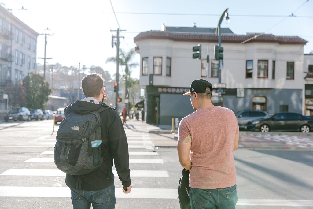 two men crossing the street at a crosswalk in a city