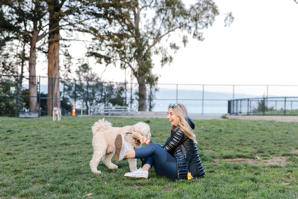 a woman sitting in the grass with her dog