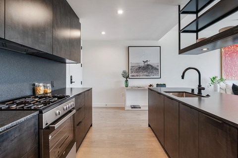 A modern kitchen with dark wood cabinets and a black stove top.