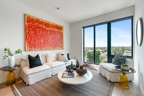 A living room with a large painting on the wall and a view of the city.